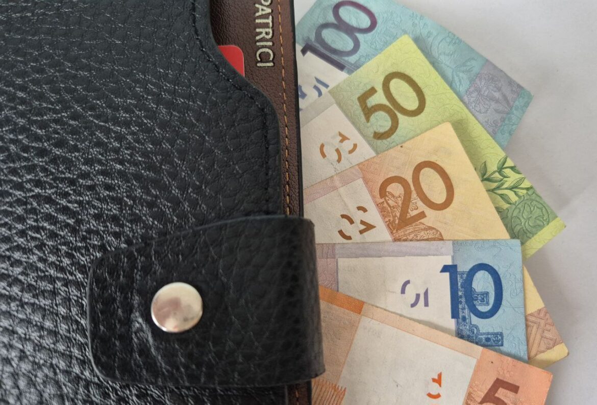 Какие выплаты в Беларуси изменятся с 1 августа и можно ли на них прожить Бумажник с купюрами разного номинала, частично выглядывающими наружу.